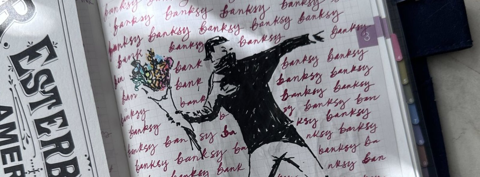 A Banksy flower thrower sketched over red lettering practice in a journal