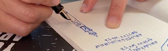 Close-up of Quynh writing with blue ink in a small grid notebook